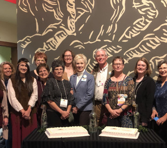 The KMA Board of Directors poses behind a table with two sheet cakes while celebrating the organization's 50th Anniversary in McPherson in 2019.