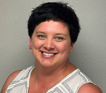 Amanda Rupp headshot with short dark hair wearing a black and white sleeveless shirt.
