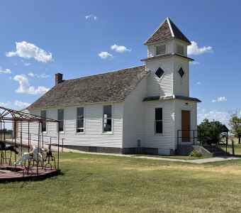 Image of a white chapel with 2.5 story bell tower in front at the Santa Fe Trail Center Museum & Research Library.