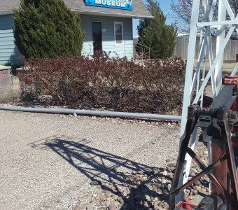 Image of a light blue building with a "Kansas Oil and Gas Museum" sign and part of an oil well in the foreground.