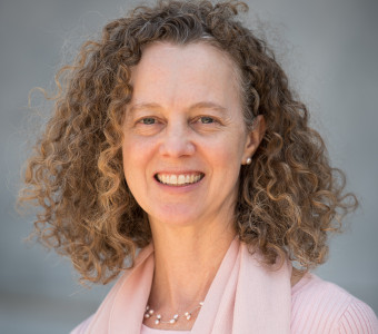 Image of Elizabeth Seaton with curly brown hair wearing a light pink scarf and sweater.