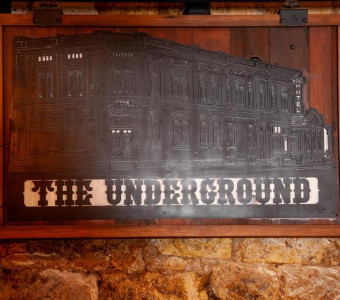 Image of a metal plaque featuring a two story hotel with "The Underground" carved below it.