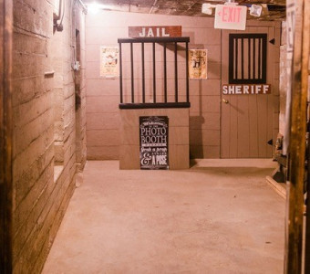Image of a cinderblock room with a jail cell photo booth and a door that says Sheriff located underground in Ellinwood.
