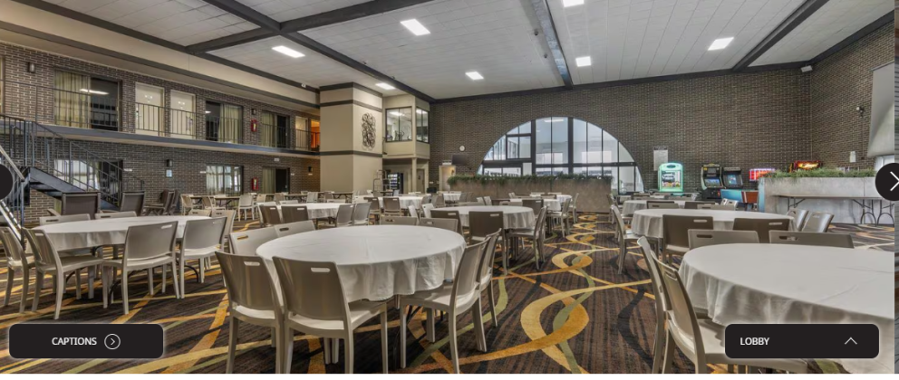 Image of the atrium area in the Best Western Angus Inn with an arched window at the back and round tables with chairs in the foreground.