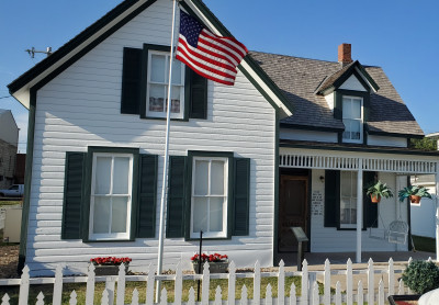 Exterior of the black and white Walter P. Chrysler Boyhood Home & Museum with an American flag flown out front