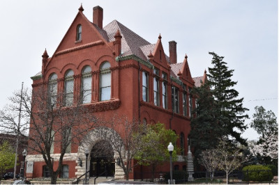 Exterior of the red brick Watkins Museum with arched windows at the top and a stone arched entrance.