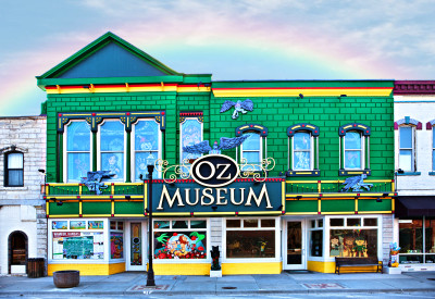 Exterior of the kelly green Oz Museum building with yellow highlights and a rainbow overhead