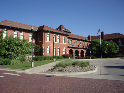 Exterior of the two-story red brick former train depot that houses the Martin and Osa Johnson Safari Museum with three visible arched doorwarys on the bottom floor.