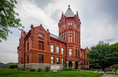Image from the left of the two storey red brick Marshall County Historic Courthouse Museum with a tower in the middle and columns surrounding the entrance