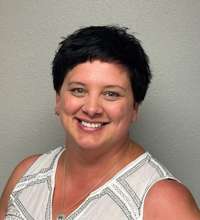 Amanda Rupp headshot with short dark hair wearing a black and white sleeveless shirt.