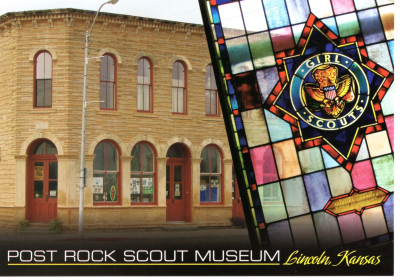 Postcard of the Post Rock Scout Museum, featuring a two story limestone building with arched windows overlaid with a stained glass window with the Girl Scout crest in the middle.