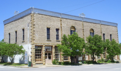 Exterior of the two story limestone Emmett Kelly Museum with the blue awning entrance flanked by trees.