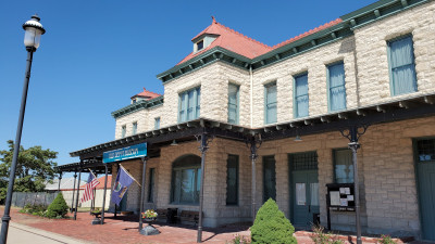 Image of the two story Franklin County Historical Society Museum, housed in the light stone and red roof Old Depot building with a porch overhang over the main floor.