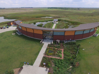 Arial image of the semicircular building housing the Kansas Wetlands Education Center with the wetlands seen beyond it.