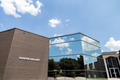 Image of the brick and mirrored glass Shafer Art Gallery with blue sky and clouds above.