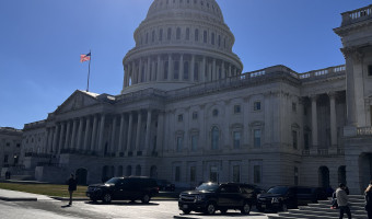 Photo of the U.S. Capitol under the sun and a bright blue cloudless sky.