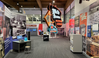 A neon sign for the "White Haven Motor Lodge" sits in the middle of an exhibit space with photos, text, and artifacts around it.