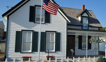 Exterior of the black and white Walter P. Chrysler Boyhood Home & Museum with an American flag flown out front