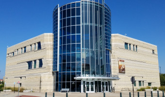 Exterior of the Flint Hills Discovery Center's entrance with curved glass tower and stone building.