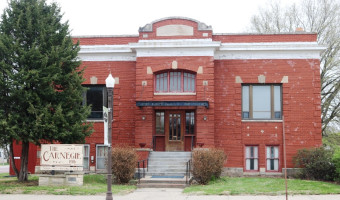 Exterior of the two story red brick Morris County Historical Society building with an arched window over the covered porch with steps and a lightpost in front.