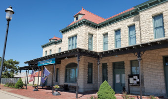 Image of the two story Franklin County Historical Society Museum, housed in the light stone and red roof Old Depot building with a porch overhang over the main floor.