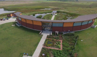Arial image of the semicircular building housing the Kansas Wetlands Education Center with the wetlands seen beyond it.