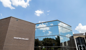 Image of the brick and mirrored glass Shafer Art Gallery with blue sky and clouds above.