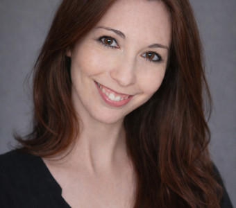 Image of Devan Tucking, a woman with long reddish brown hair wearing a black shirt.