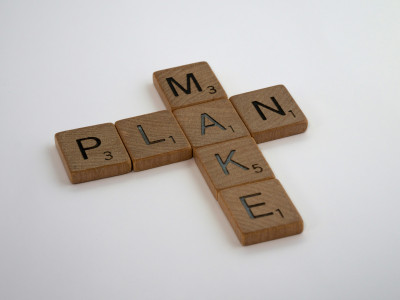 Wooden scrabble tiles are used to create the word plan horizontally and make vertically, using a shared "a" tile.