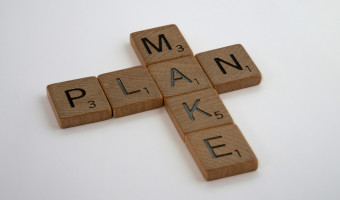 Wooden scrabble tiles are used to create the word plan horizontally and make vertically, using a shared "a" tile.
