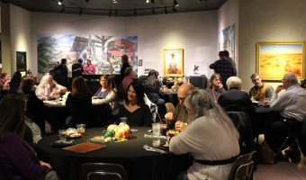 Image of people seated at tables and standing with art on the walls in the background at the Traveling Reception during the 2025 KMA Conference at Barton County Community College's Shafer Art Gallery in Great Bend.